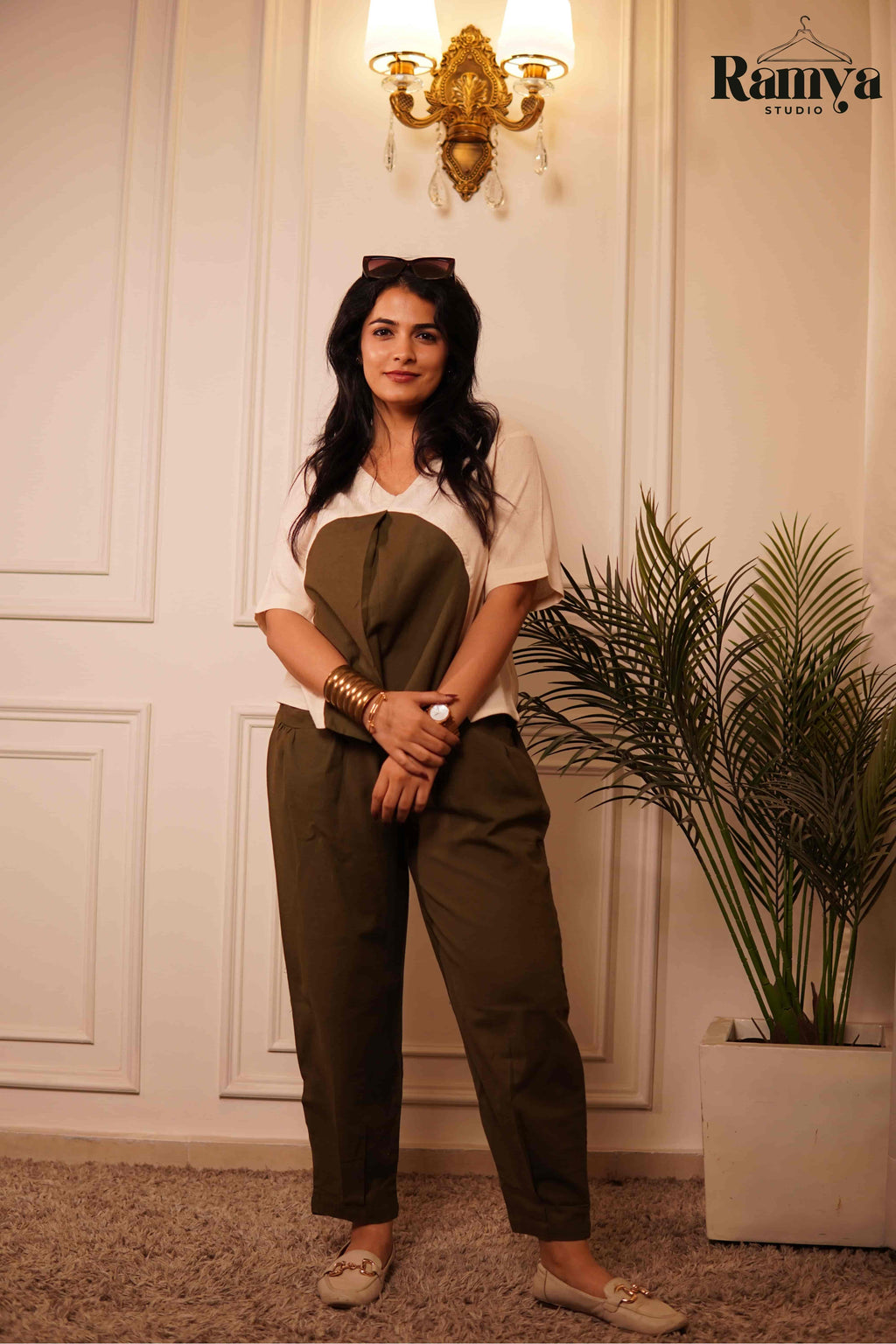 Ramya Studio's Olive Orb Set: A structural cream top with an oversized olive green circular graphic paired with high-waisted olive pants in a luxury home setting.
