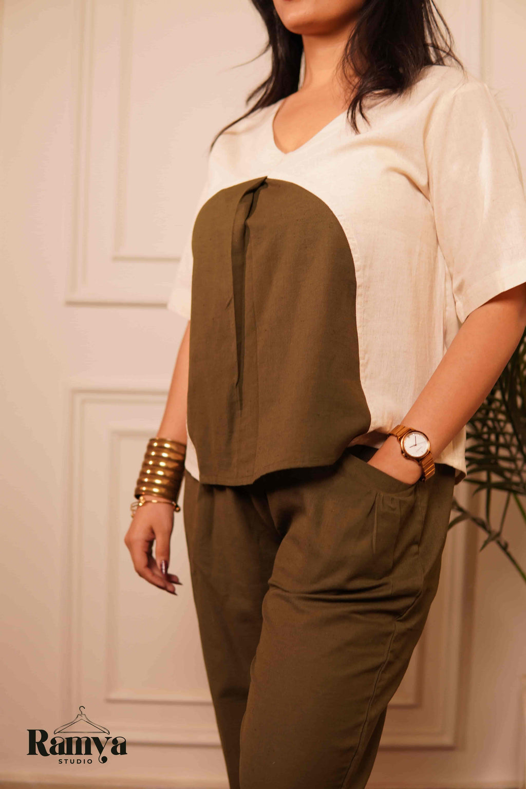Ramya Studio's Olive Orb Set: A structural cream top with an oversized olive green circular graphic paired with high-waisted olive pants in a luxury home setting