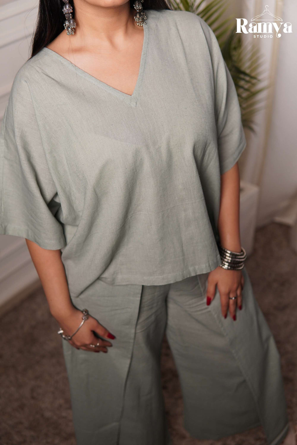 Chic airport look and travel fashion inspiration: A model styling a comfortable, earthy sage green co-ord set with a brown leather shoulder bag and neutral cross-strap sandals.