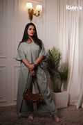 A model posing in Ramya Studio's sage green essential co-ord set, featuring a relaxed-fit, boxy short-sleeve top with a V-neckline and matching wide-leg trousers with front overlay panels.