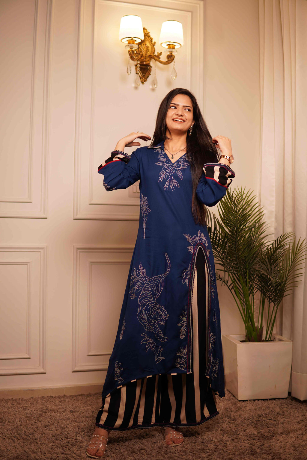 A model at Ramya Studio posing in the 'The Blue Bagh' set, featuring a deep indigo blue high-slit kurta with silver tiger motifs and matching black-and-white striped wide-leg palazzos."