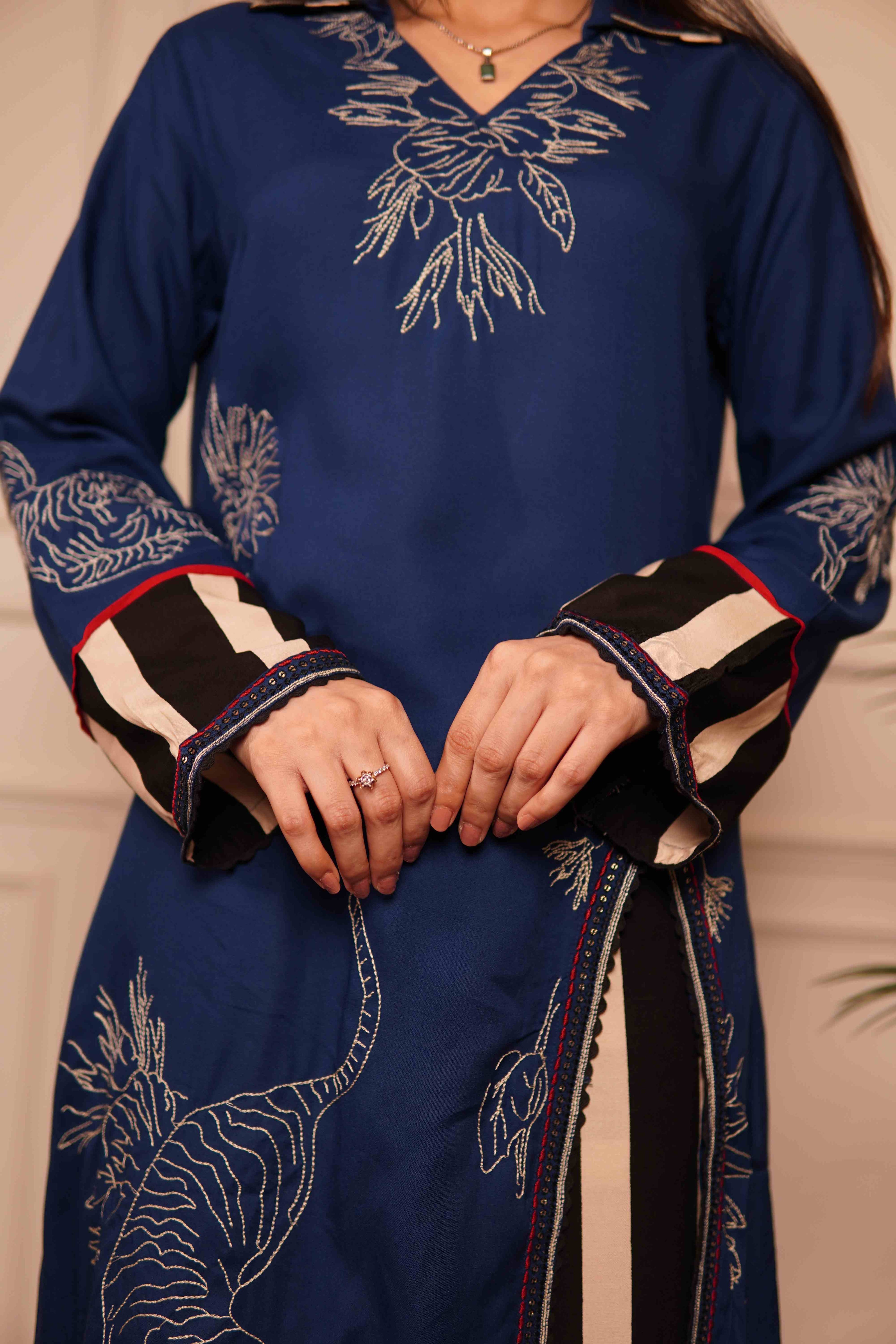 Close-up of the silhouette of a blue long-line kurta with a deep side slit, showing the contrast between the intricate tiger embroidery and the bold geometric striped pants.