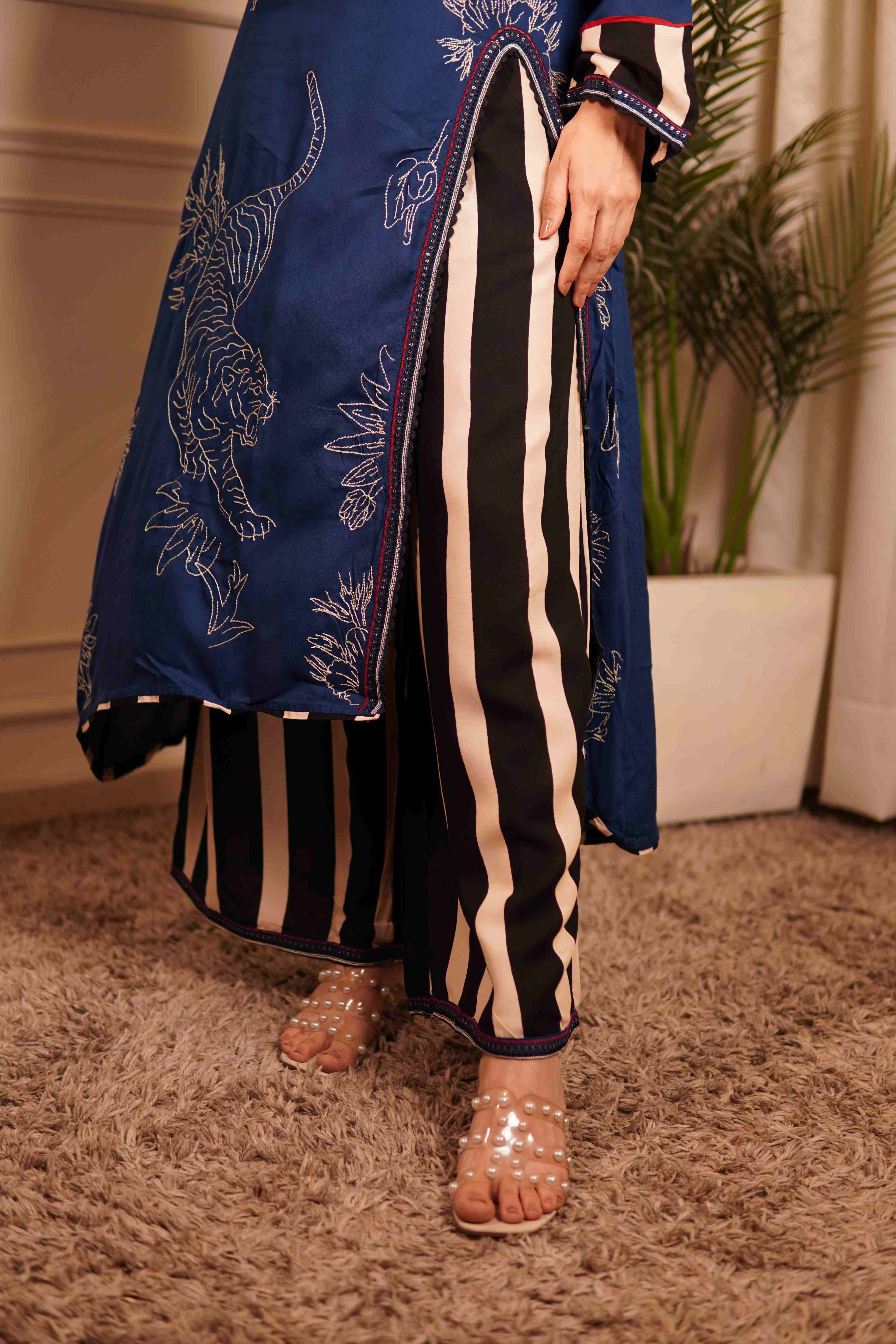 Ramya deep blue tiger motif kurta with black and white striped wide-leg trousers and transparent beaded sandals.