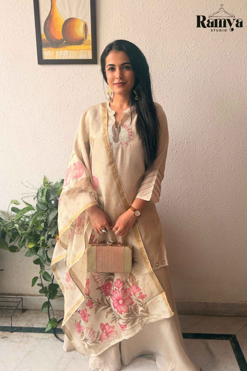 Full-length front view of a model wearing Ramya Studio's Geet Ivory Sharara Set holding a gold clutch and draped in a pink floral organza dupatta.
Perfect for Diwali