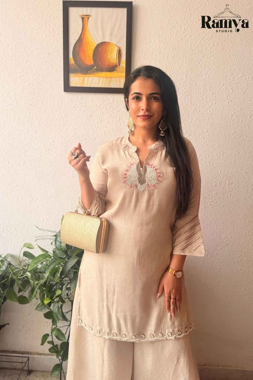 Frontal pose of a model showcasing the notched neckline with pink embroidery and pin-tuck sleeves on the Geet Ivory tunic