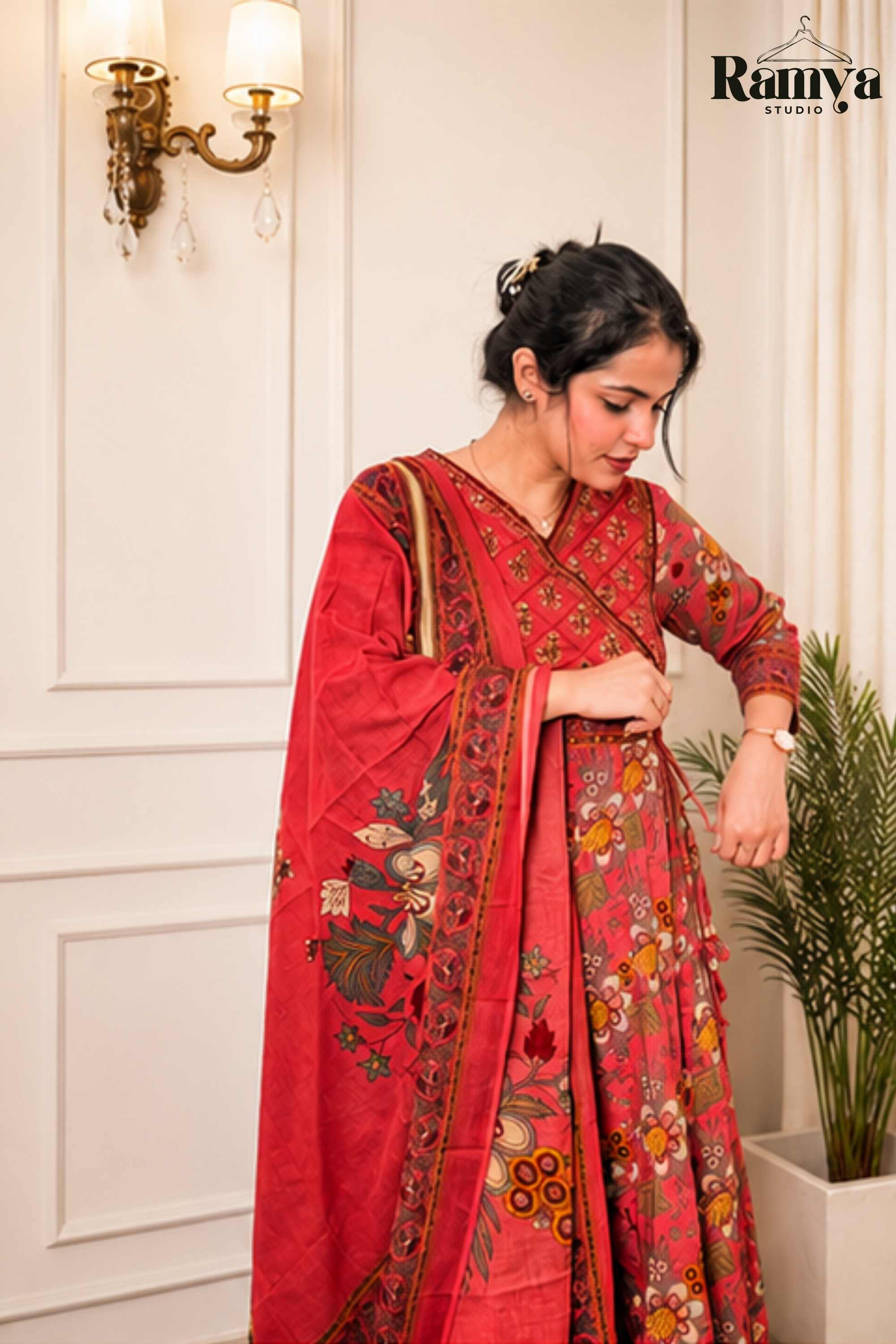 Close-up profile of a woman adjusting the side tie-up knot on a crimson printed Angrakha bodice with intricate V-neckline embroidery and draped printed dupatta."