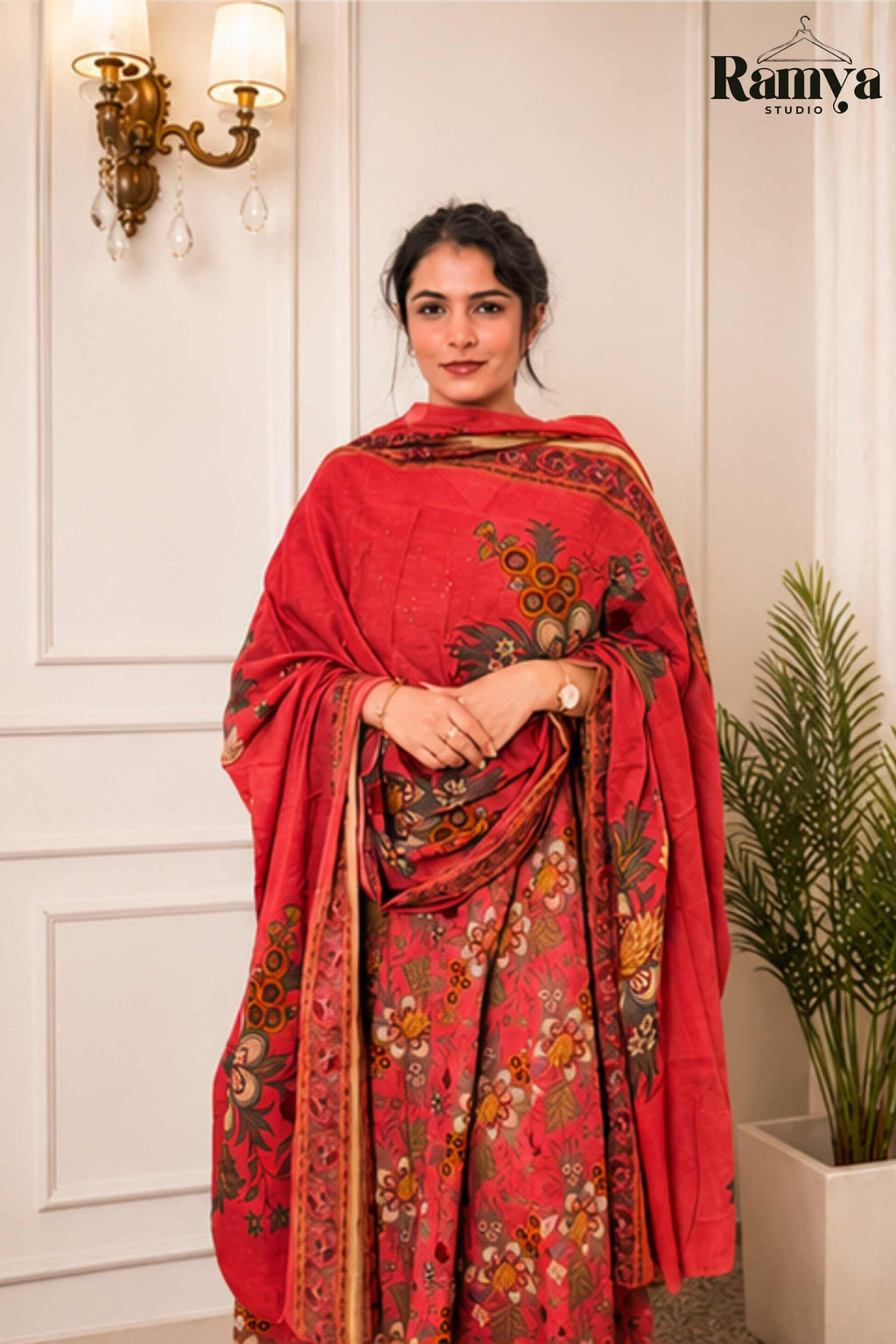 Half-length portrait of a model gracefully holding a crimson floral printed dupatta wrapped across the front of a red Angrakha Anarkali kurta.