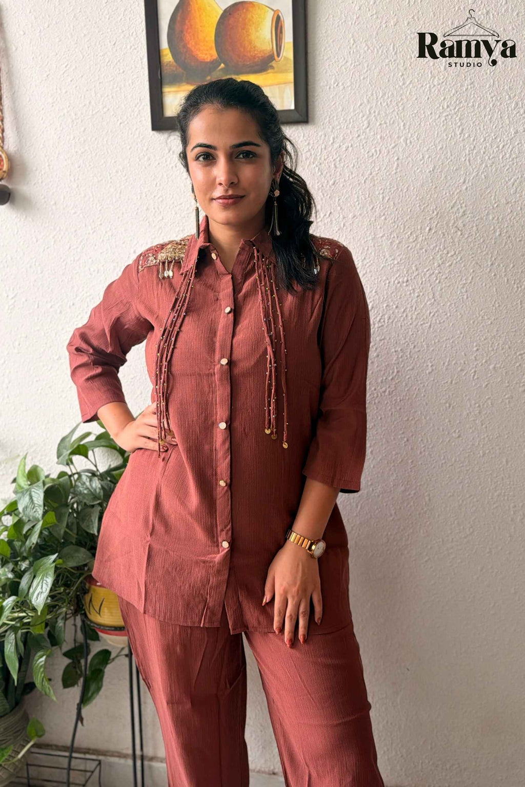 Frontal pose of a model wearing Ramya Studio's 'Rumi' set in terracotta rust with shoulder embroidery and beaded coin strands.